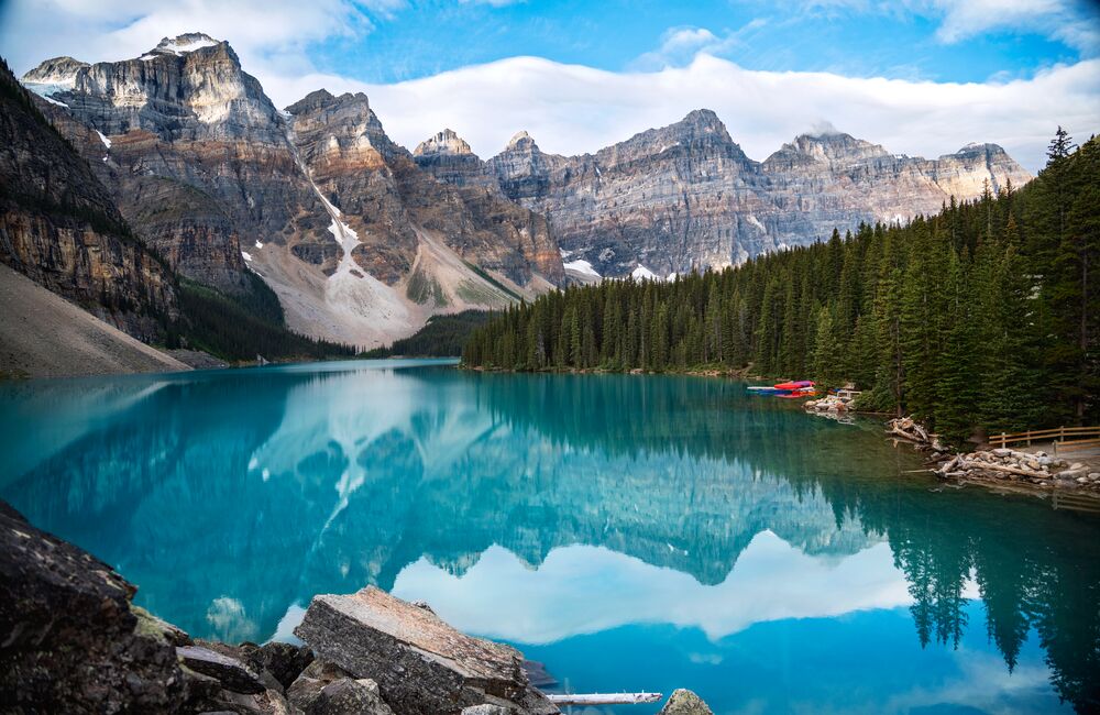 The turquoise waters of Moraine Lake reflecting mountain peaks on a blue bird day in Banff NAtional Park.